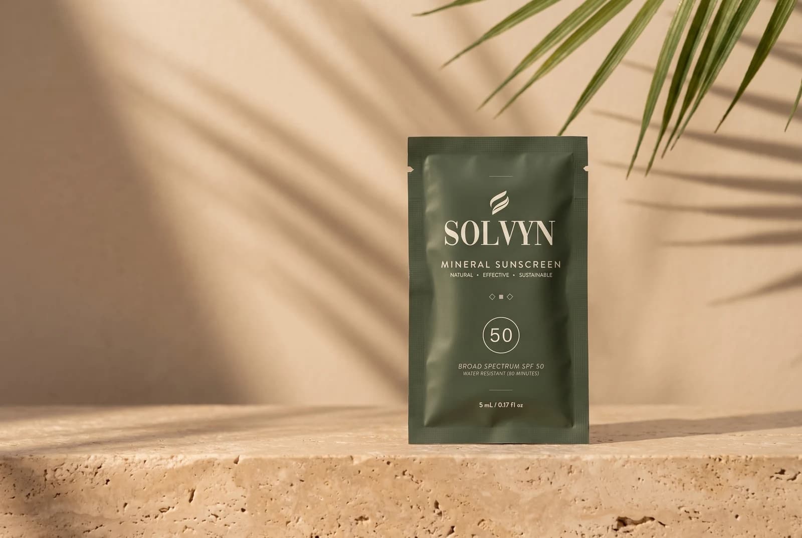 Solvyn mineral sunscreen SPF 50 sachet standing upright on a travertine ledge, with palm-frond shadows falling across a warm plaster wall behind it