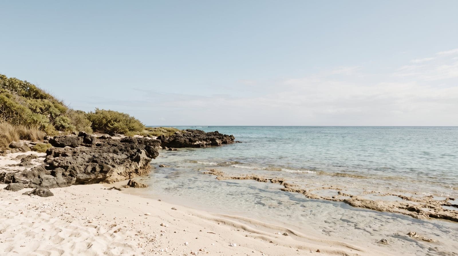 A Hawaiian shoreline with shallow water over a pale reef flat.