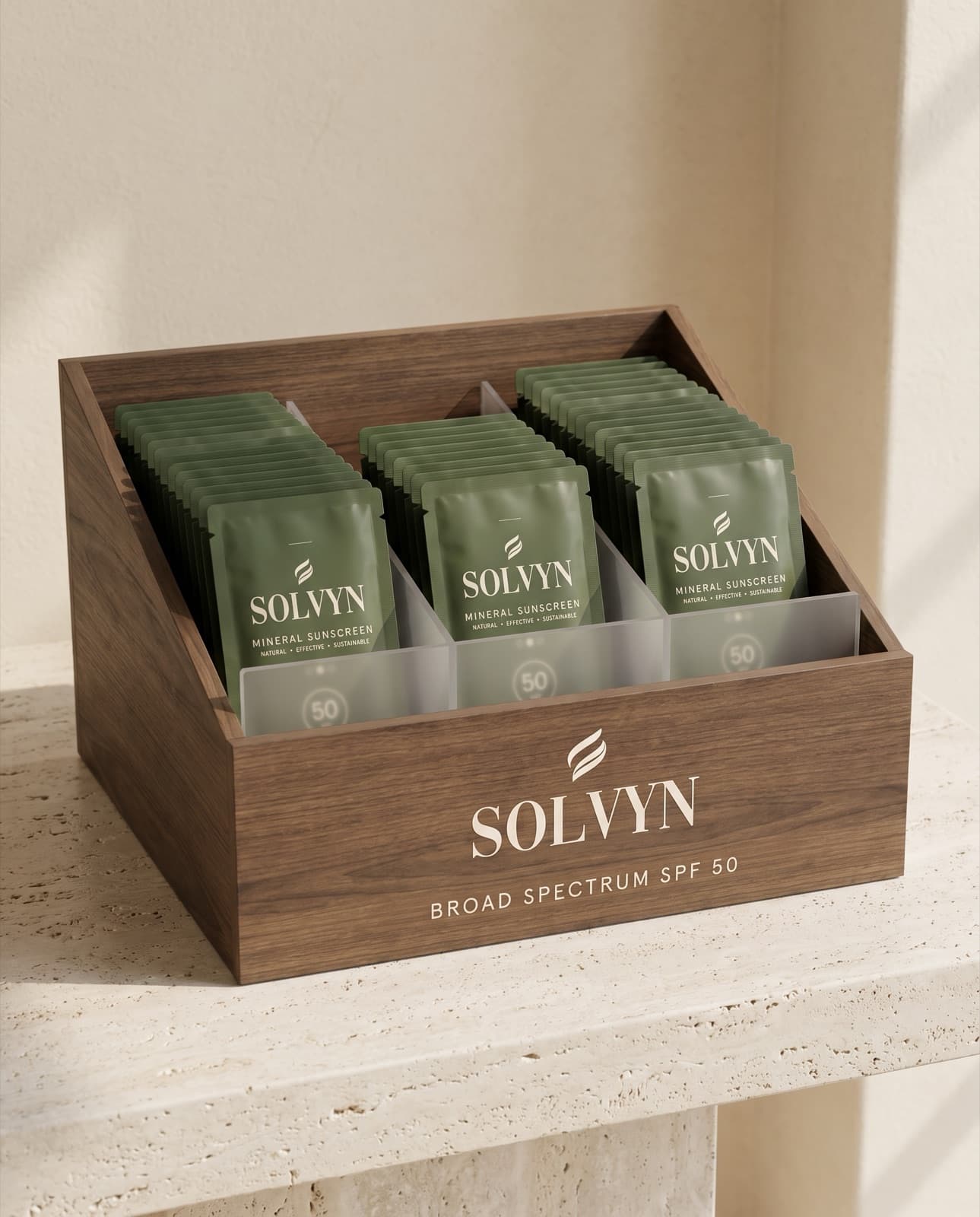 Walnut and frosted-acrylic display box holding sealed Solvyn Shield sachets, upright on a travertine counter
