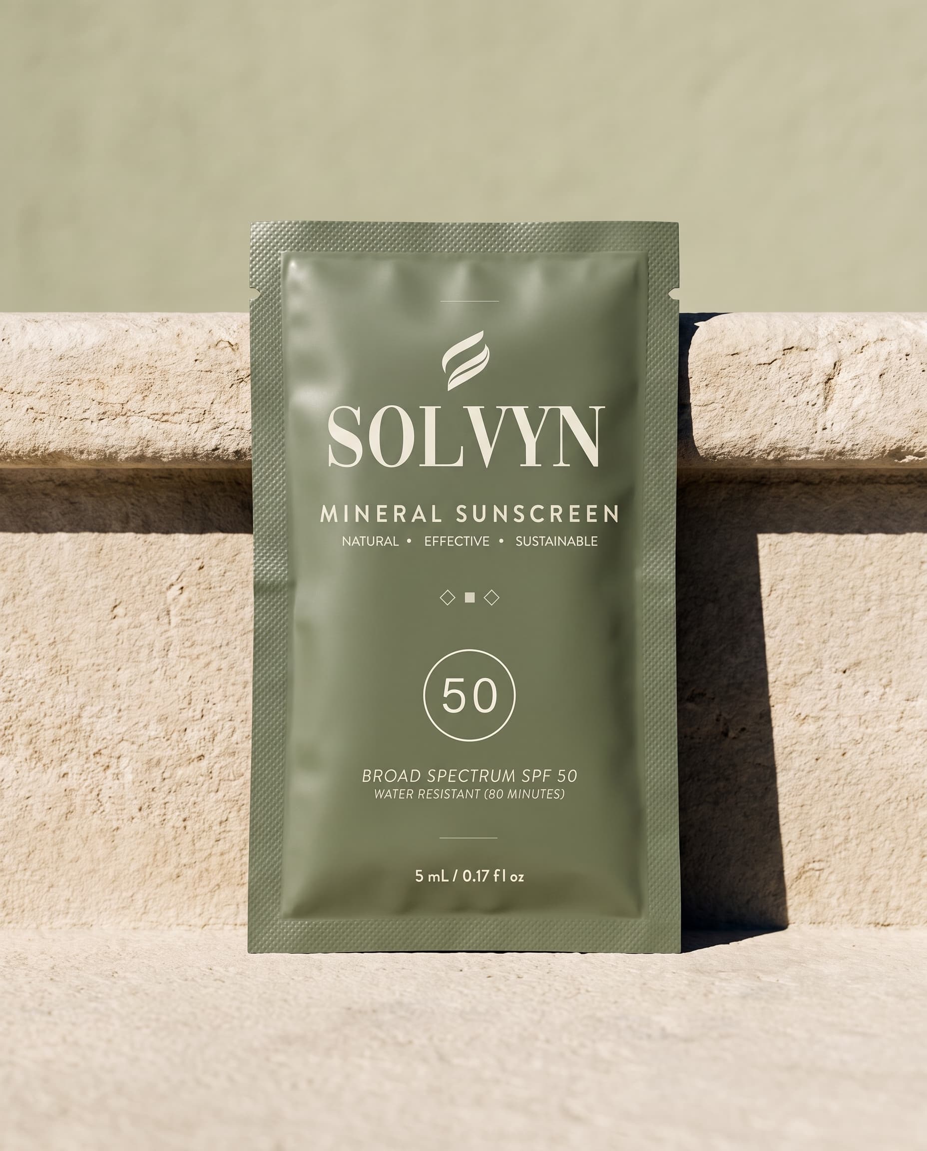 A sealed Solvyn Shield sachet standing on a sun-bleached limestone step in hard midday light, casting a crisp shadow