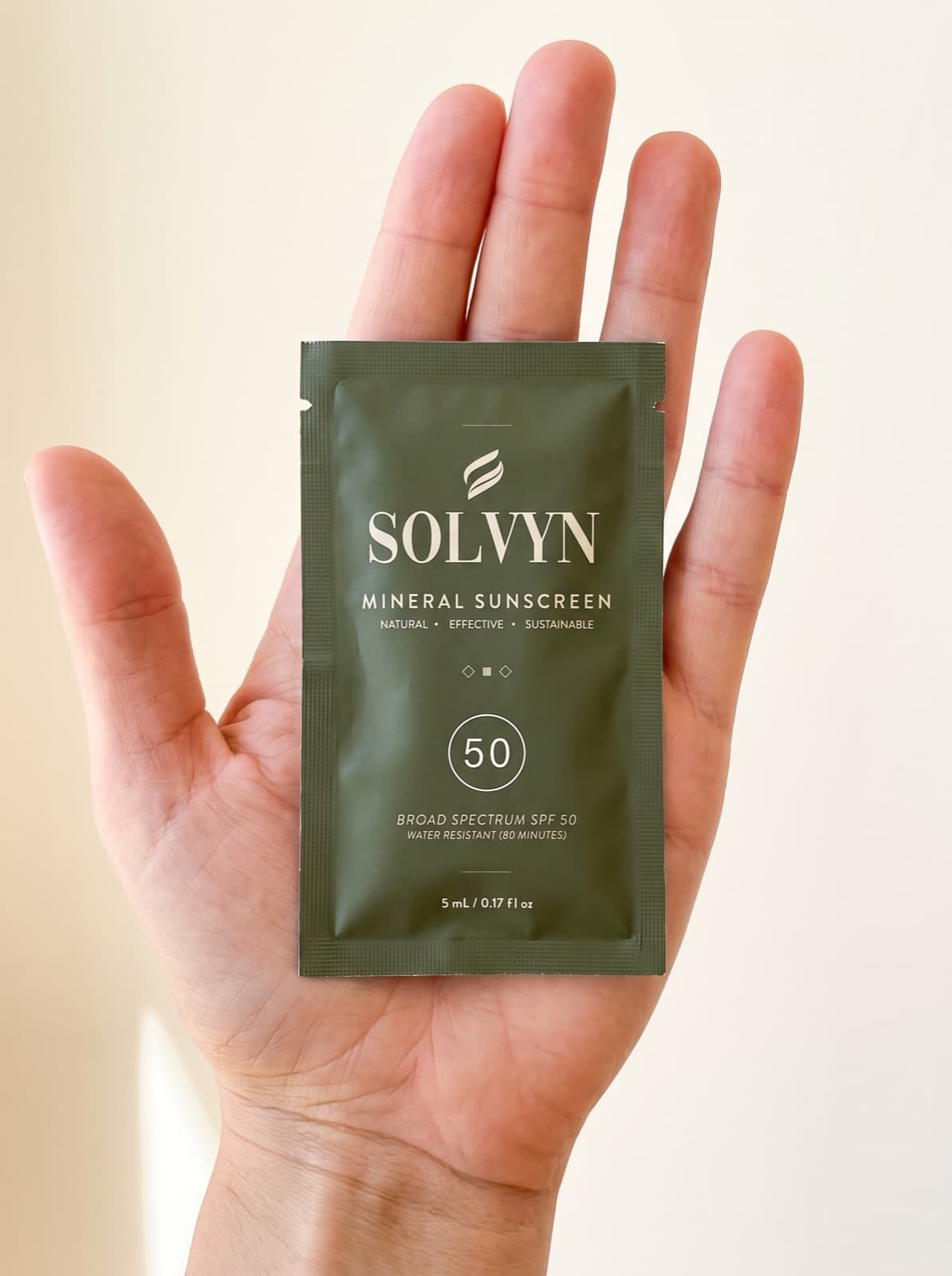 The Solvyn Shield sachet lying in an open palm, showing its true size — a 9 cm single-dose packet