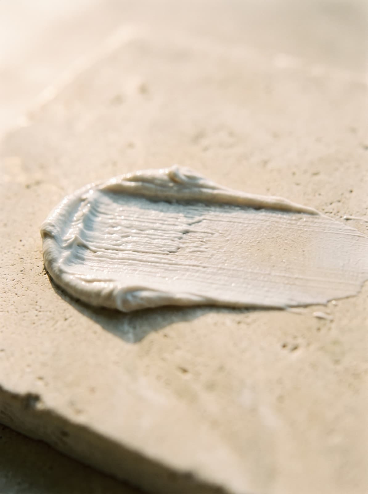 A swatch of Solvyn Shield on warm limestone — thick and opaque at one end, pressed out almost invisibly sheer at the other