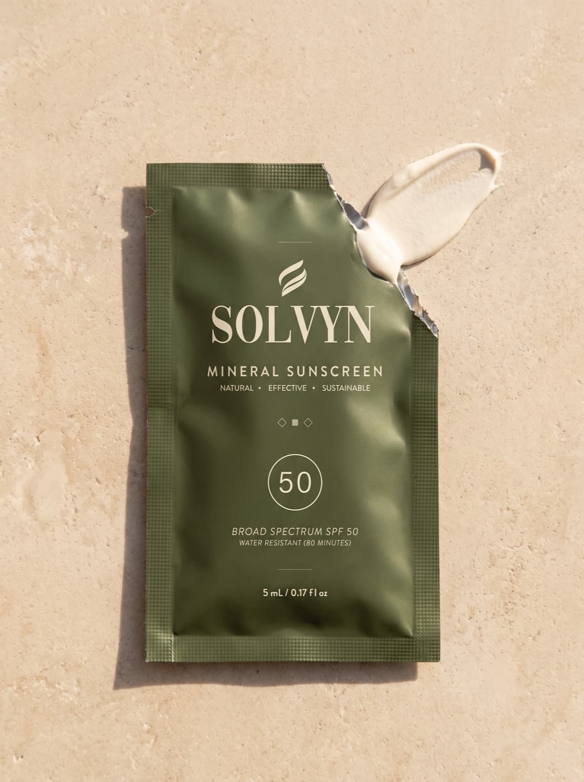 A Solvyn Shield sachet torn open along its serrated edge beside a stroke of mineral cream