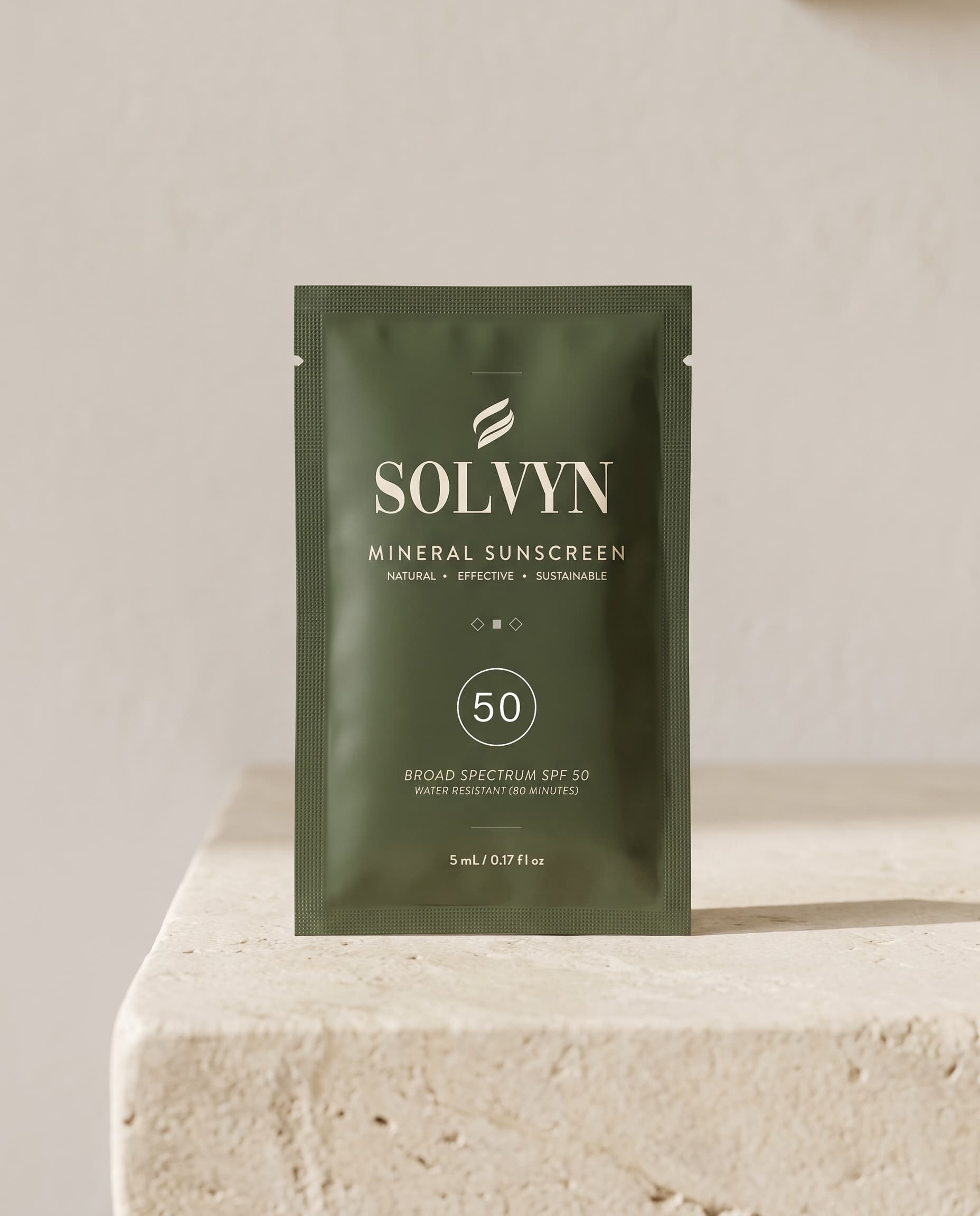 A sealed Solvyn Shield sachet standing on a honed limestone vanity ledge against a bare lime-plaster wall